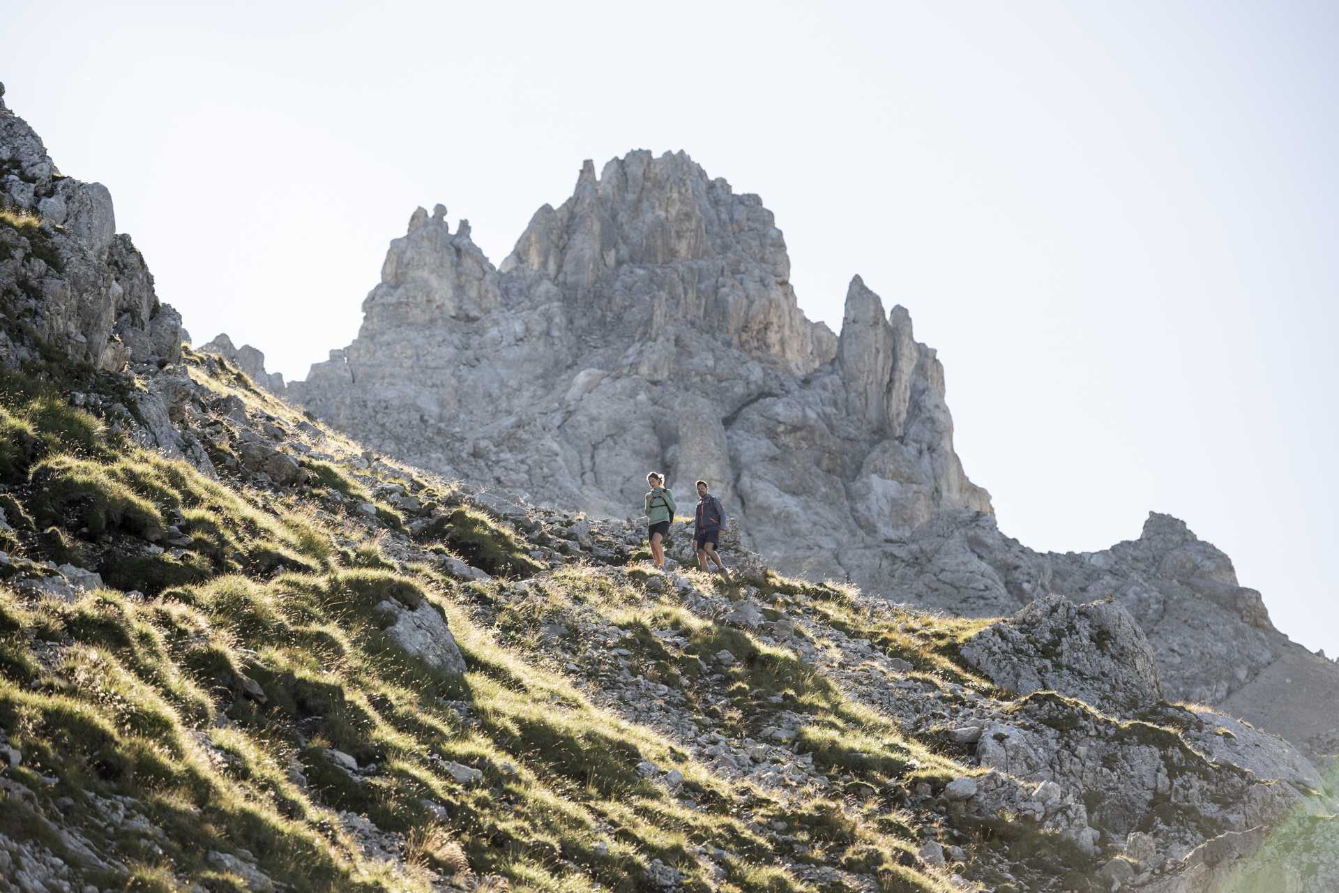 2 Personen bei einer Bergtour. Im Hintergund ein großer Berggipfel